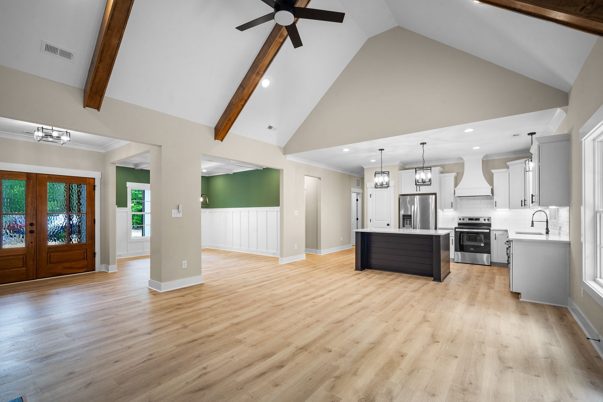 A large empty room with hardwood floors and a ceiling fan.