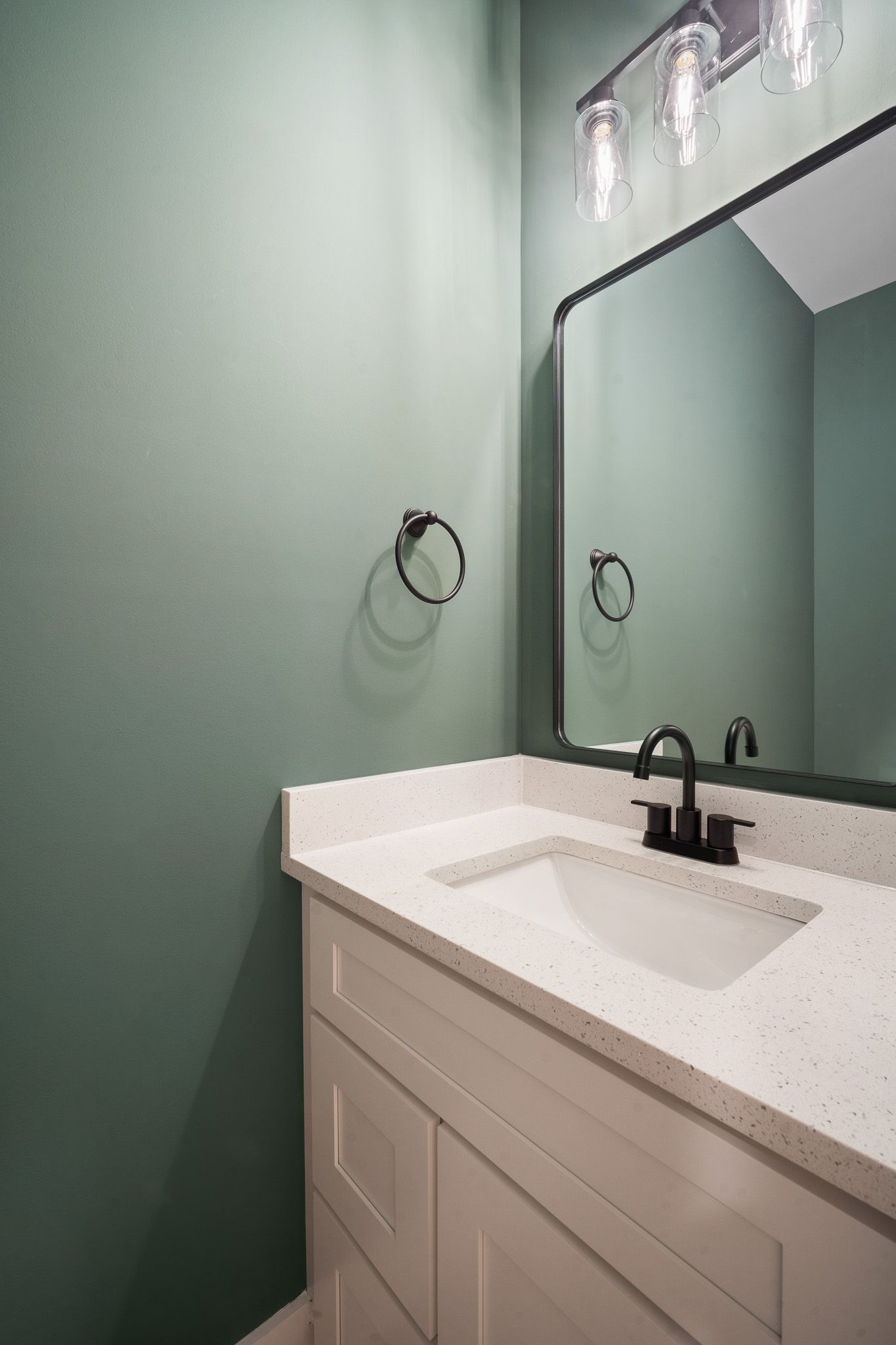 A bathroom with a sink , mirror and light.