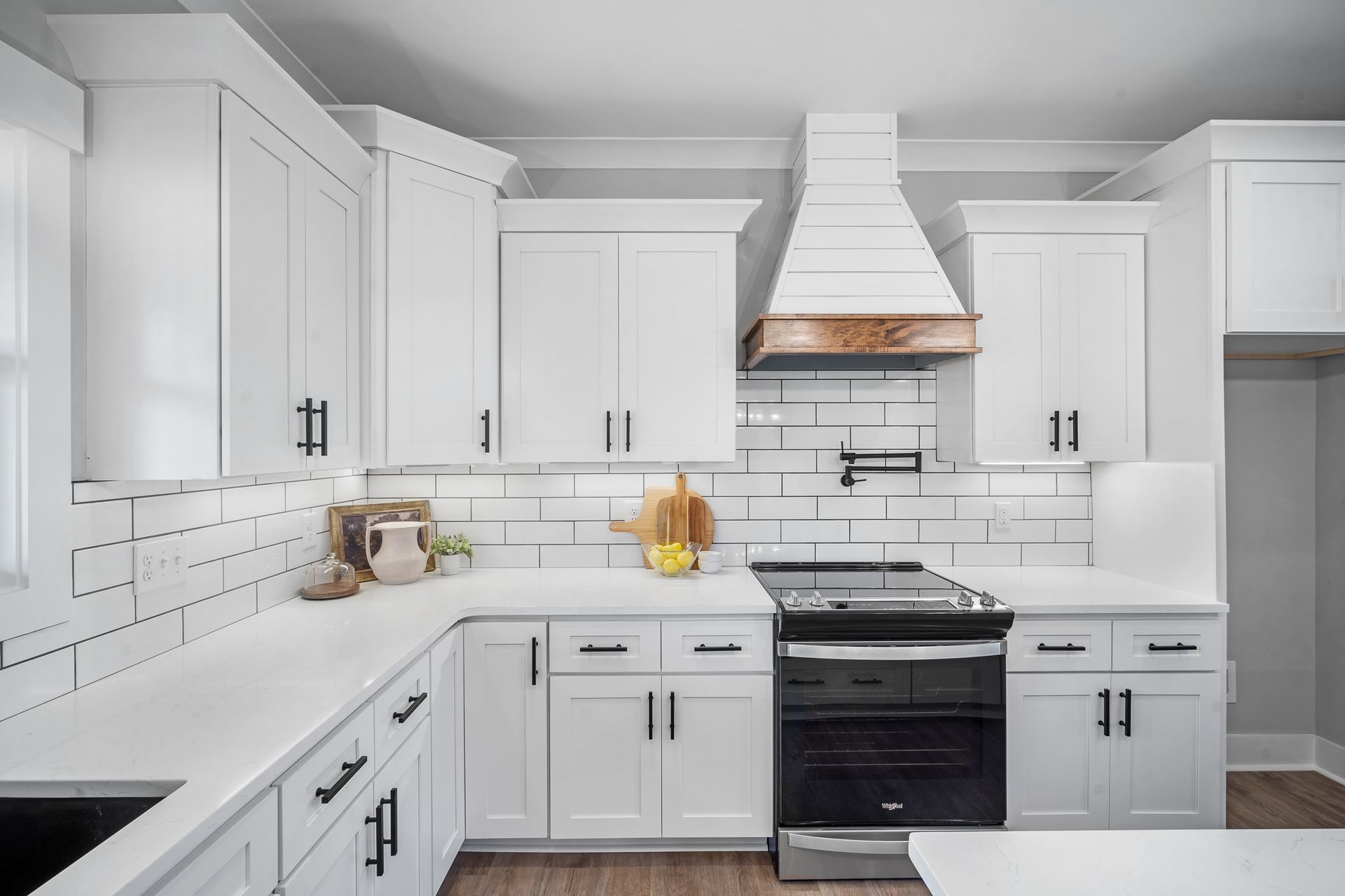 A kitchen with white cabinets , black appliances , and a stove.