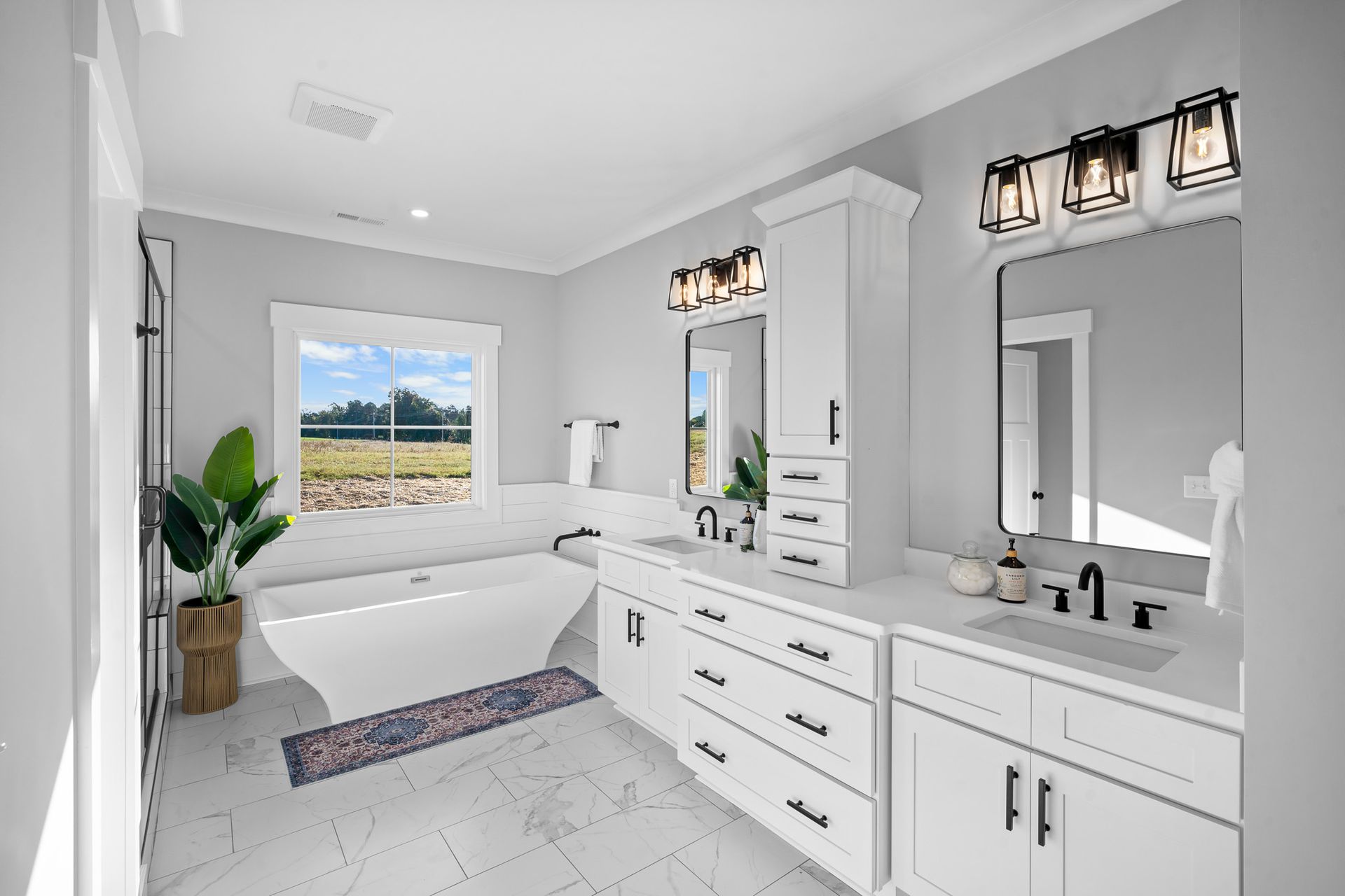 A bathroom with two sinks , a tub , and a window.