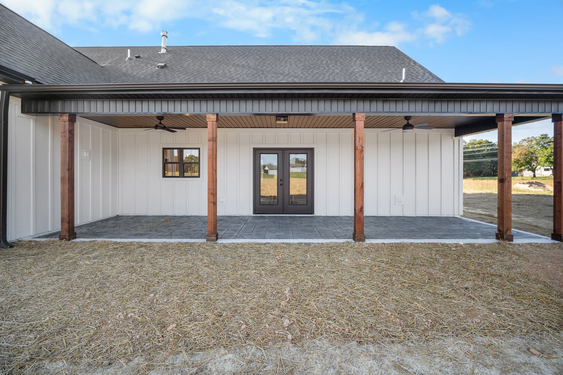 The back of a white house with a covered patio and a porch.