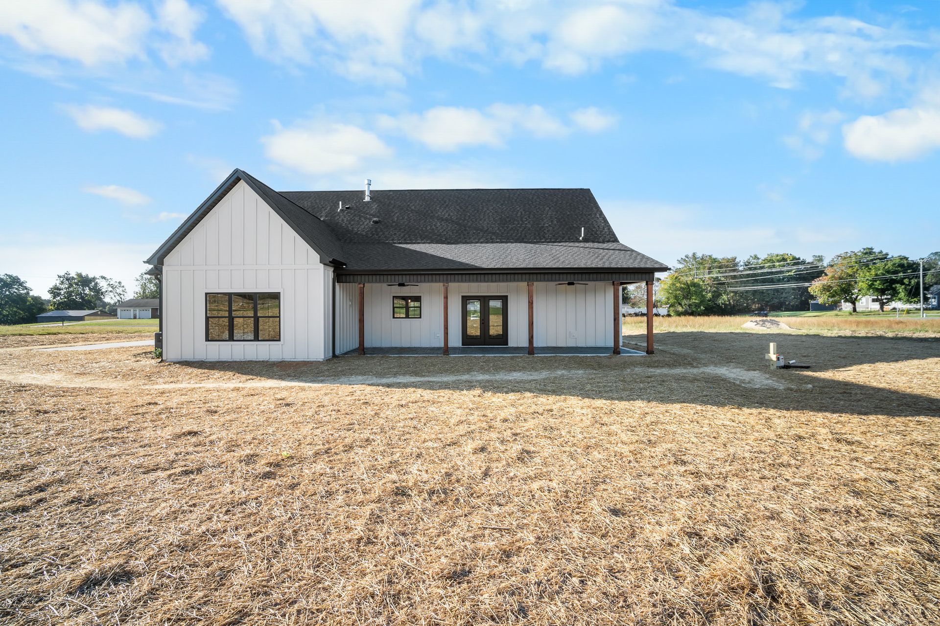 A white house is sitting in the middle of a dirt field.