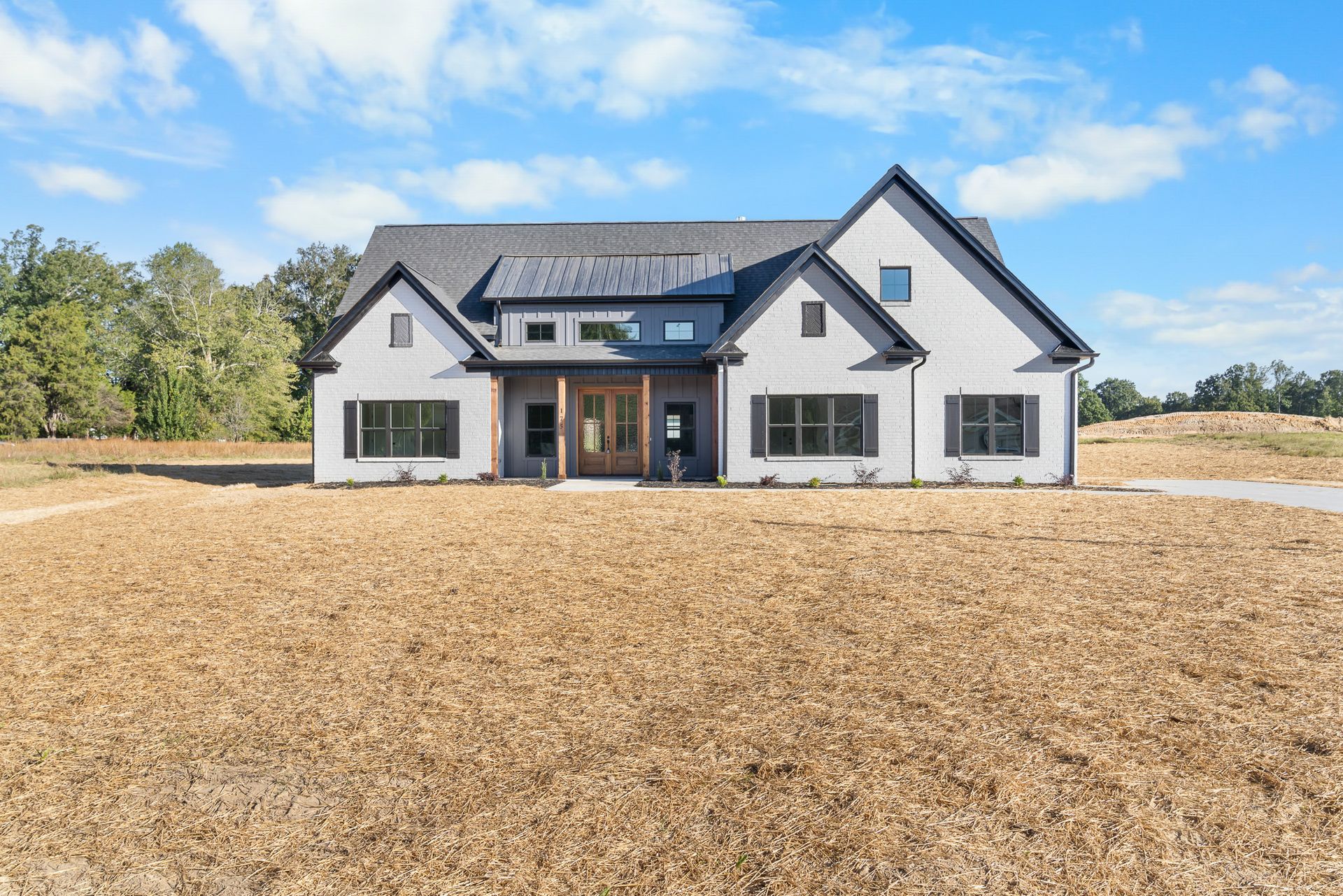 A large white house is sitting on top of a dirt field.
