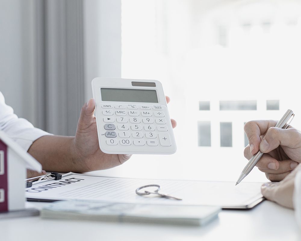 Man is Holding a Calculator and Writing on a Paper
