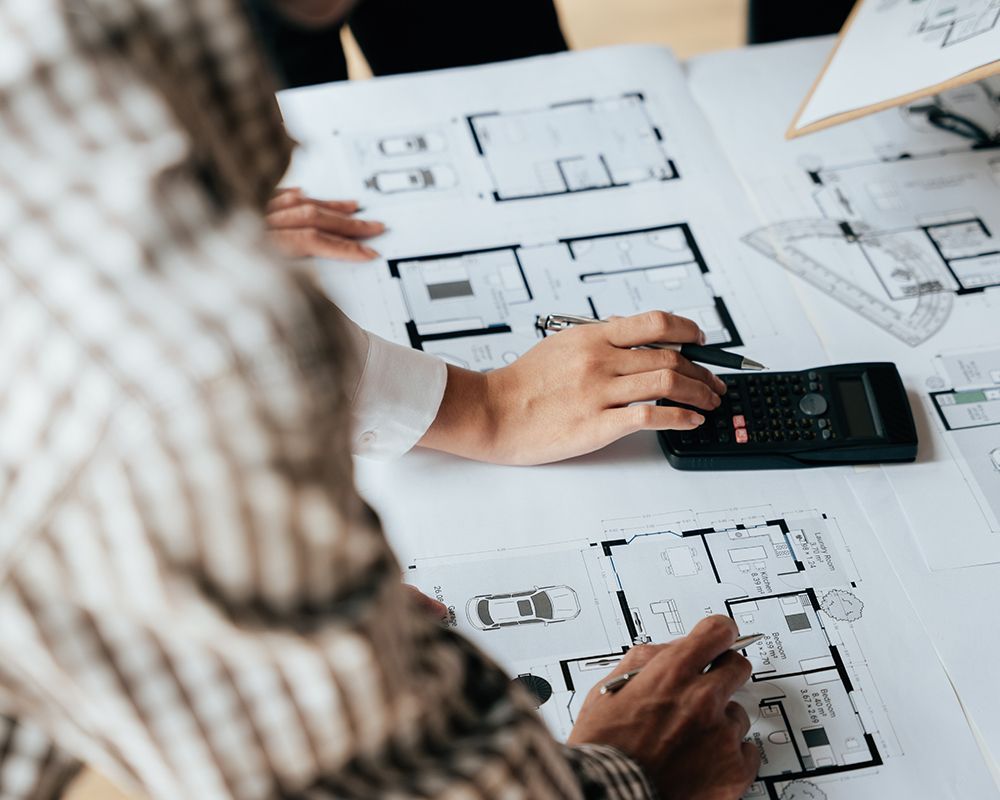 Worker Looking on a Floor Plan and Using a Calculator