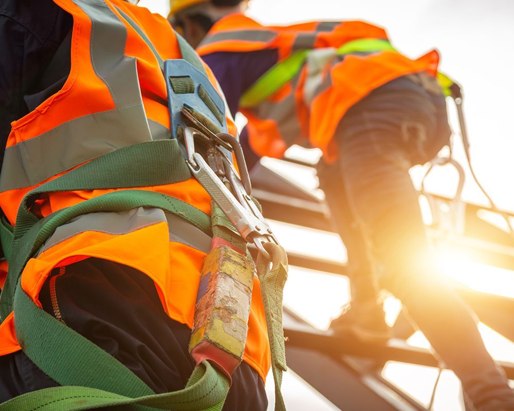 Workers Wearing Safety Vests and Harnesses are Working on a Roof