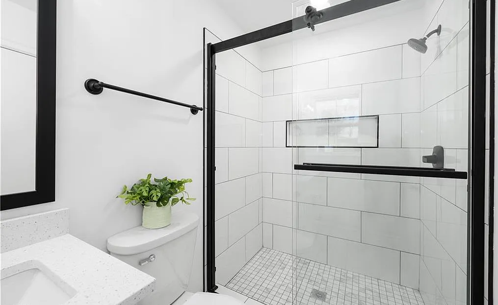 A bathroom with a toilet , sink , shower and mirror.