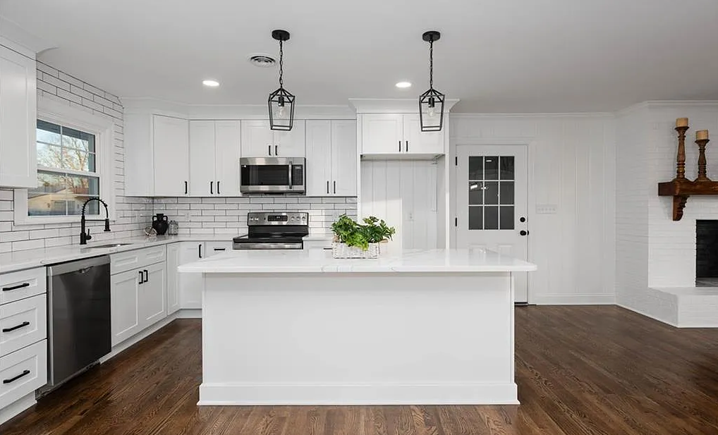 A kitchen with white cabinets , stainless steel appliances , and a large island.
