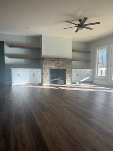 An empty living room with a fireplace and a ceiling fan.
