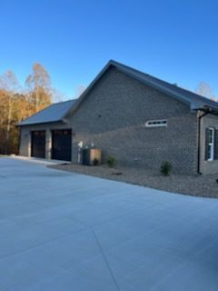 A brick house with a concrete driveway in front of it