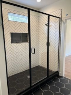 A shower with a black frame and white tiles