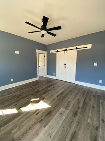 An empty room with a ceiling fan and sliding barn doors.