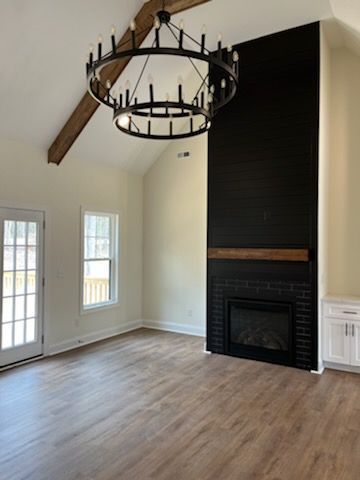 An empty living room with a fireplace and a chandelier.