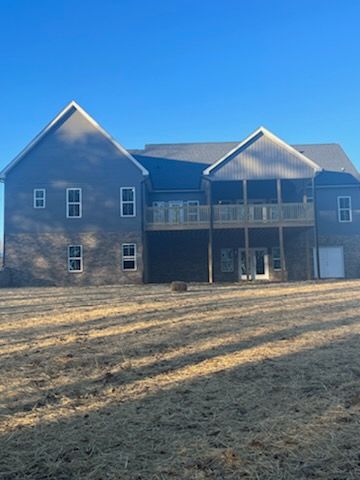 A large house with a lot of windows is sitting on top of a lush green field.