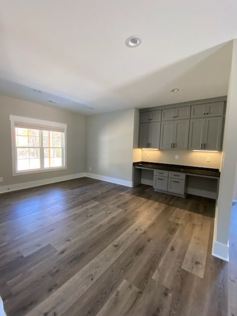 An empty room with hardwood floors and gray cabinets