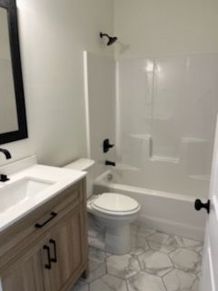 A bathroom with a toilet , sink , bathtub and mirror.