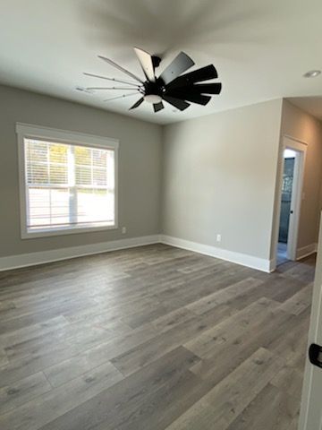 An empty living room with hardwood floors and a ceiling fan.