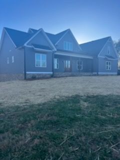 A large house with a lot of windows is sitting on top of a lush green field.