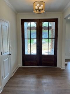 An empty room with a double door and a chandelier.