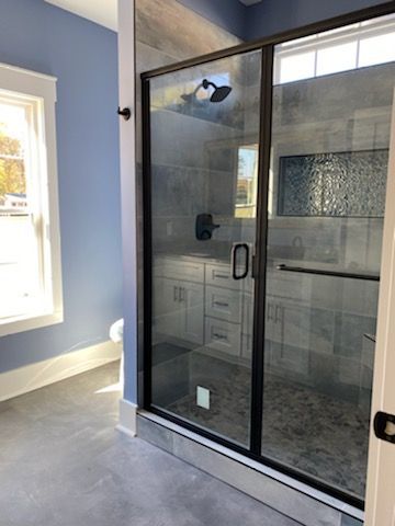 A bathroom with a walk in shower and a window.