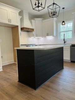 A kitchen with white cabinets and a black island