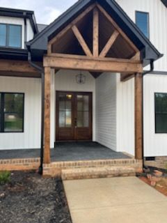 A white house with a wooden porch and a black roof