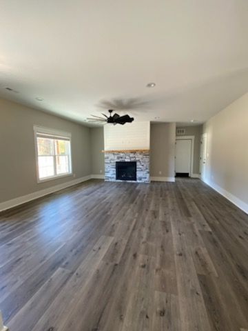 An empty living room with hardwood floors and a fireplace.