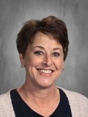 a woman is smiling for a picture in front of a gray background .