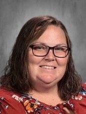 a woman wearing glasses and a red shirt is smiling for a picture .