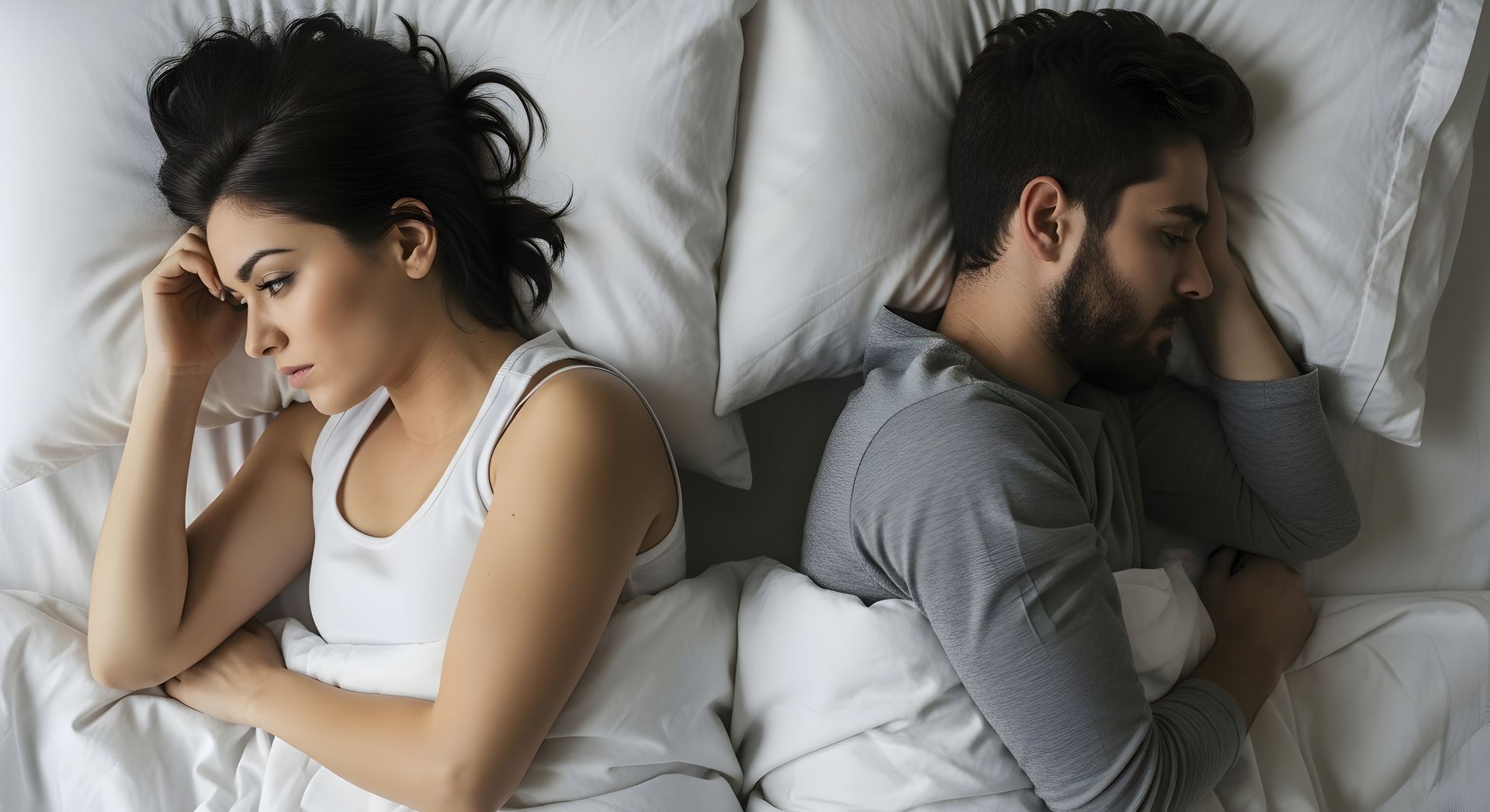 Couple in bed, facing away from each other. Woman is looking away with a concerned expression. Man appears to be sleeping.