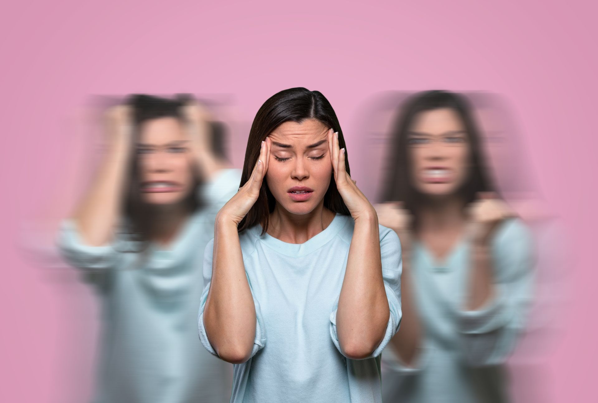 Woman with hands on head, blurred versions on either side. Pink background, showing stress.