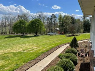 A house with a lush green lawn and a walkway leading to it.
