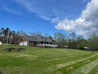 A large house is sitting on top of a lush green field.