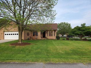 A brick house with a large lush green lawn and a white garage door.