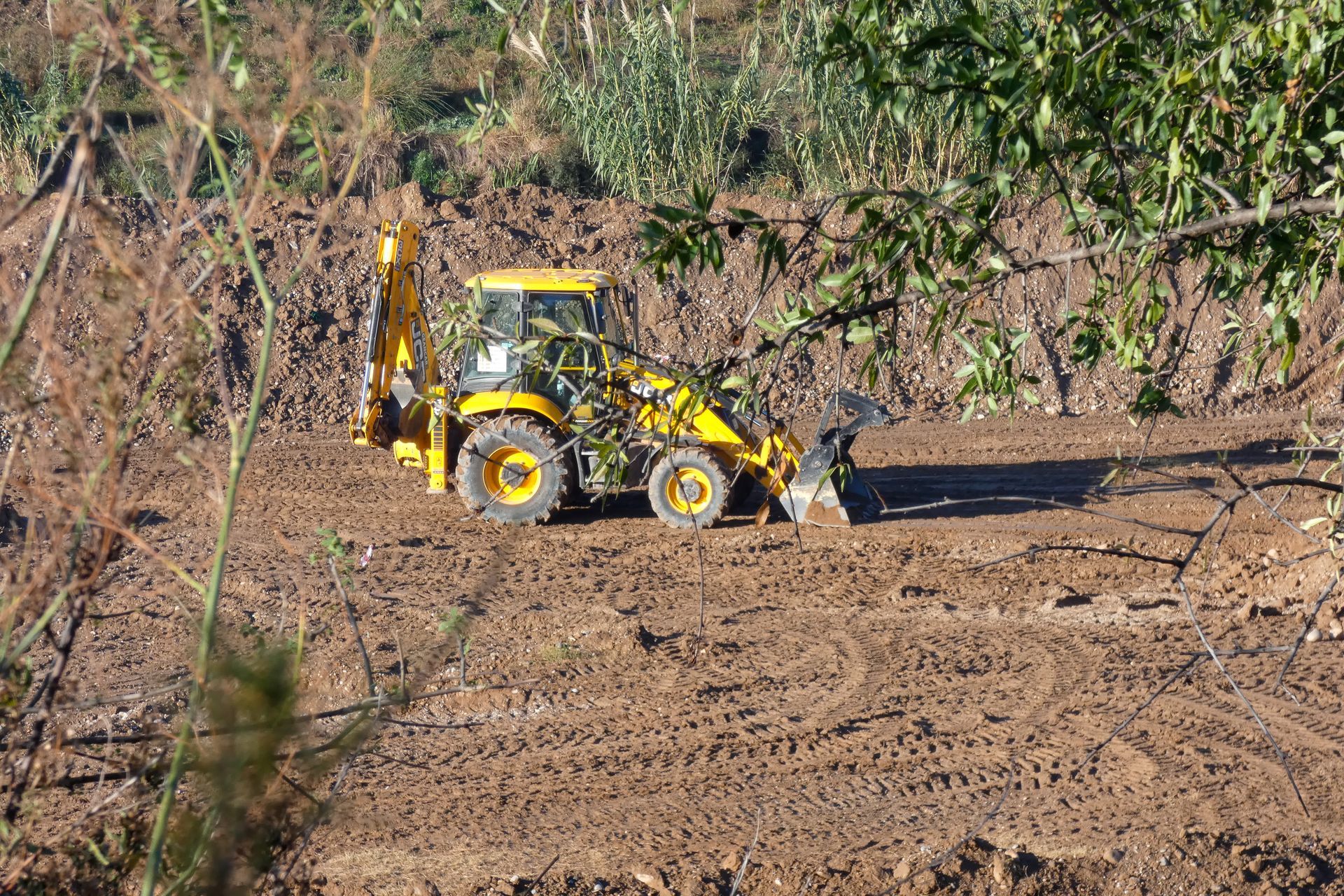 A yellow tractor is driving through a dirt field.