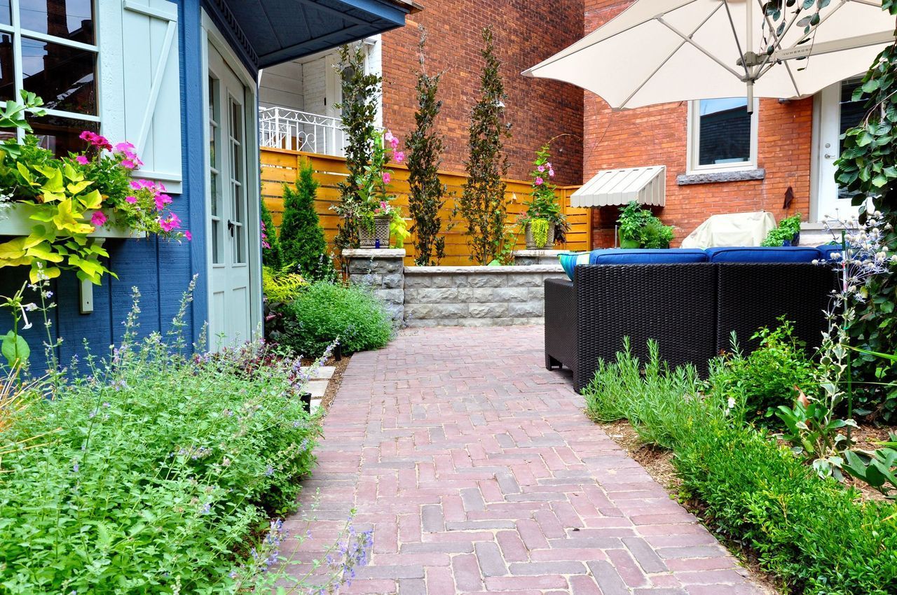 A brick walkway leading to a patio with umbrellas and furniture.