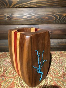 A wooden vase with a tree on it is sitting on a table.