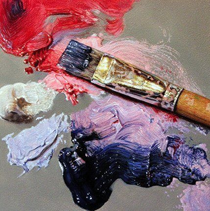 A brush is sitting on top of a palette of paint