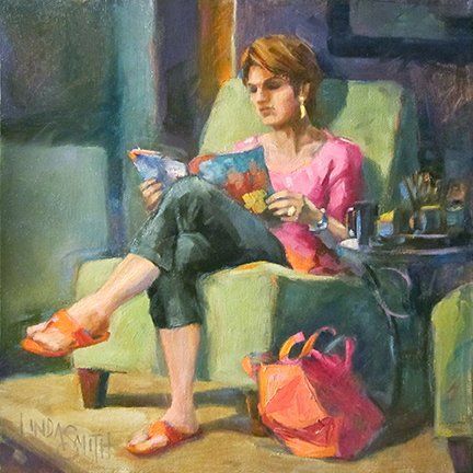 A woman is sitting in a chair reading a book.