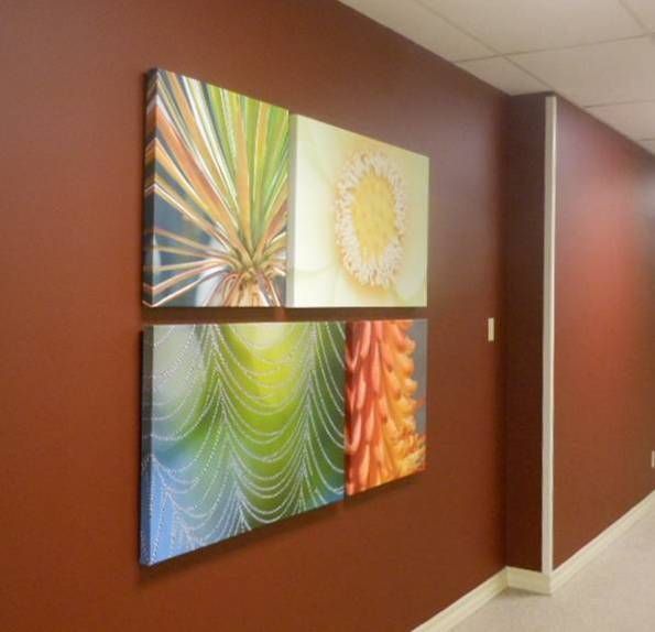 Four paintings are hanging on a red wall in a hallway