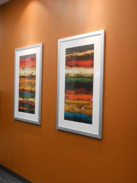 Two framed pictures are hanging on an orange wall