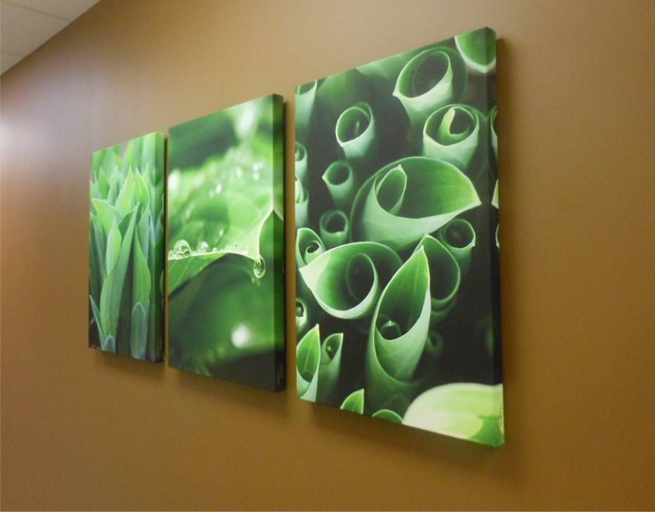 Three green paintings are hanging on a brown wall