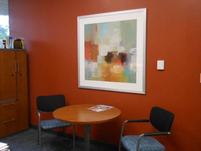 A room with a table and chairs and a painting on the wall
