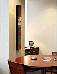 A dining room with a round table and chairs and a painting on the wall.