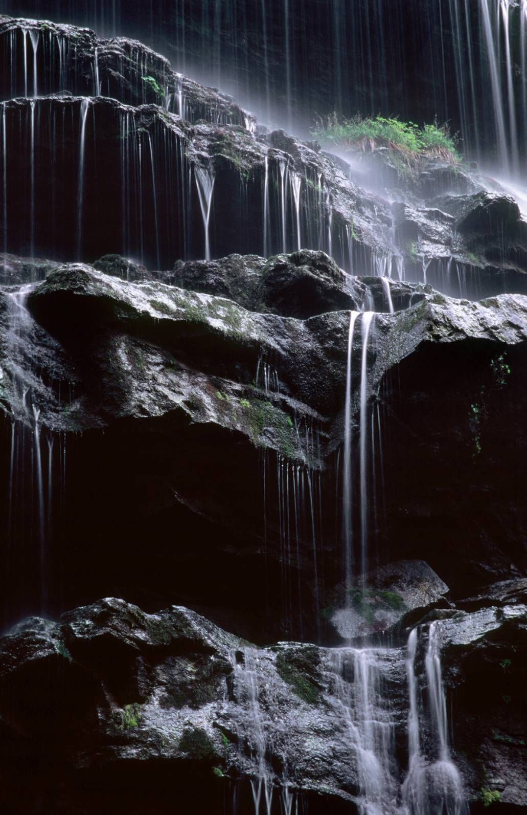 A waterfall is surrounded by rocks in the dark.