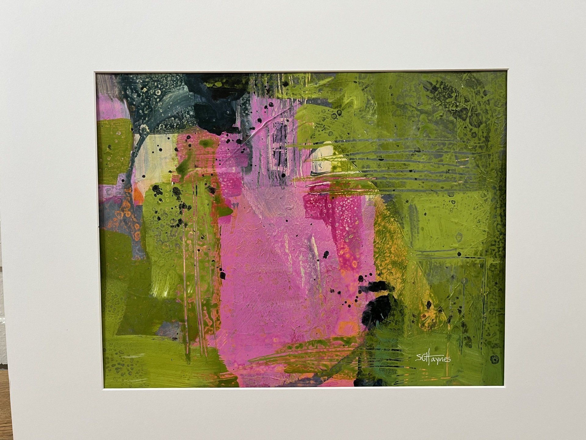 A painting of a pink and green background with a white frame.