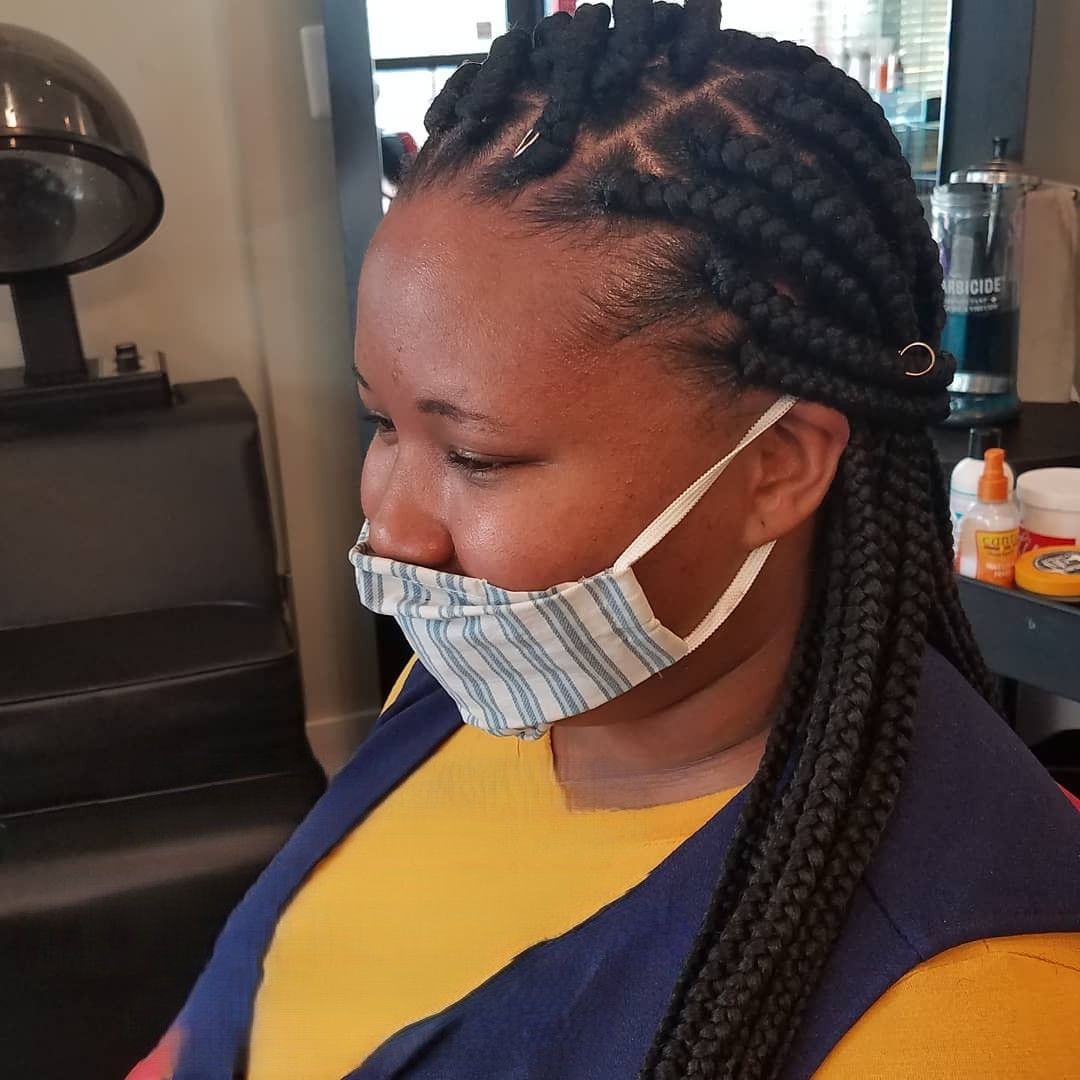 Woman with braided hair wearing a face mask in a salon.