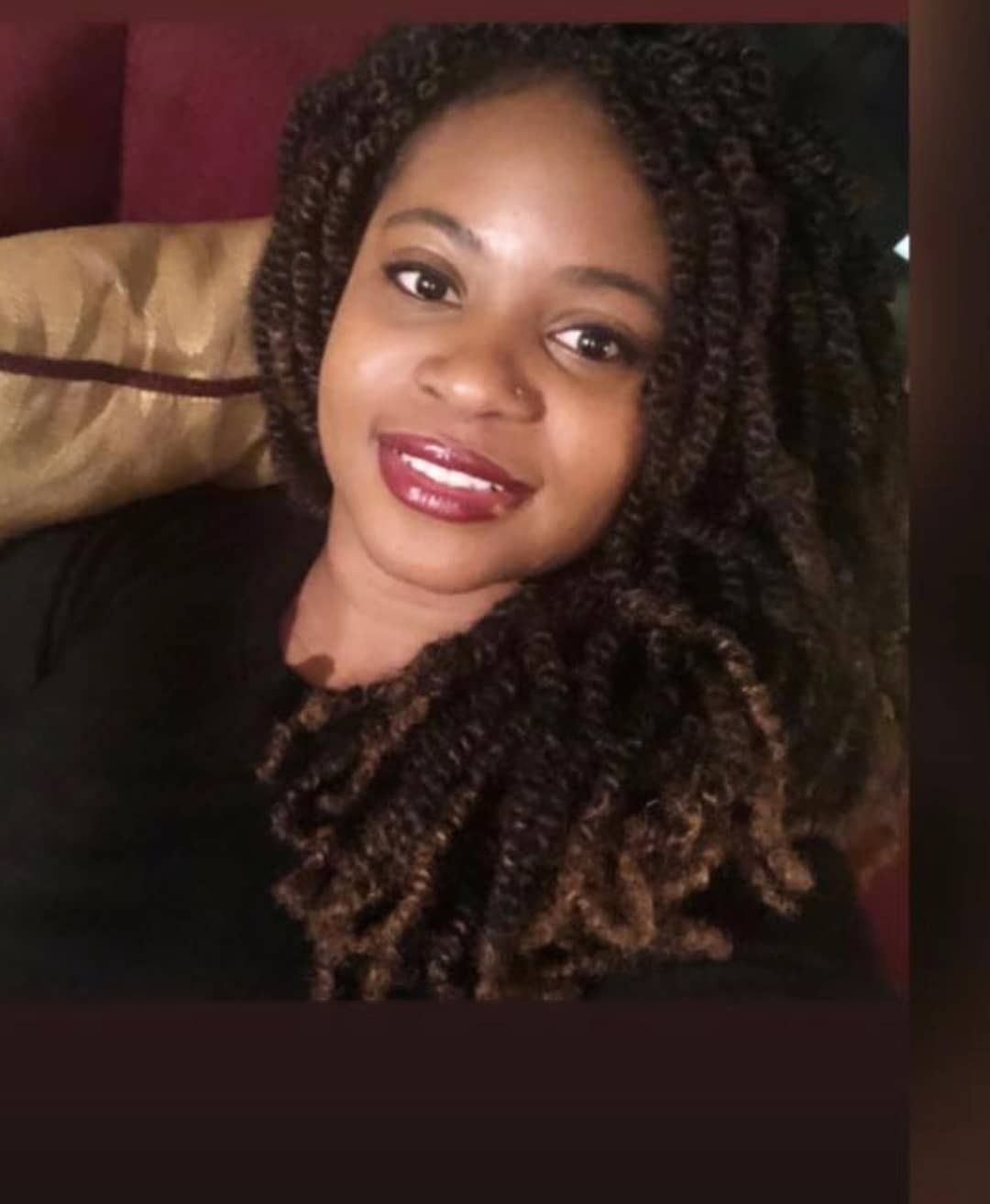 Woman with brown twisted braids and red lipstick smiles.