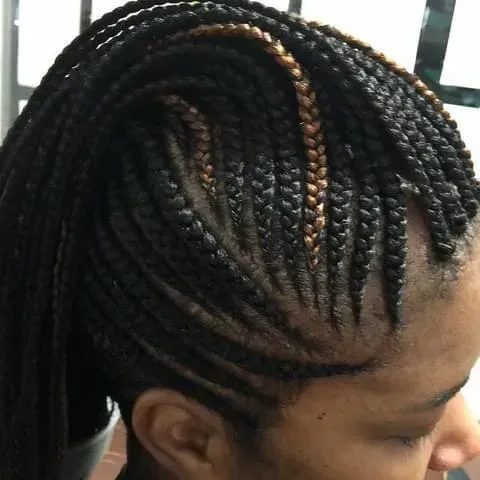 Close-up of a person's head with cornrow braids. Some braids have a brown hue.