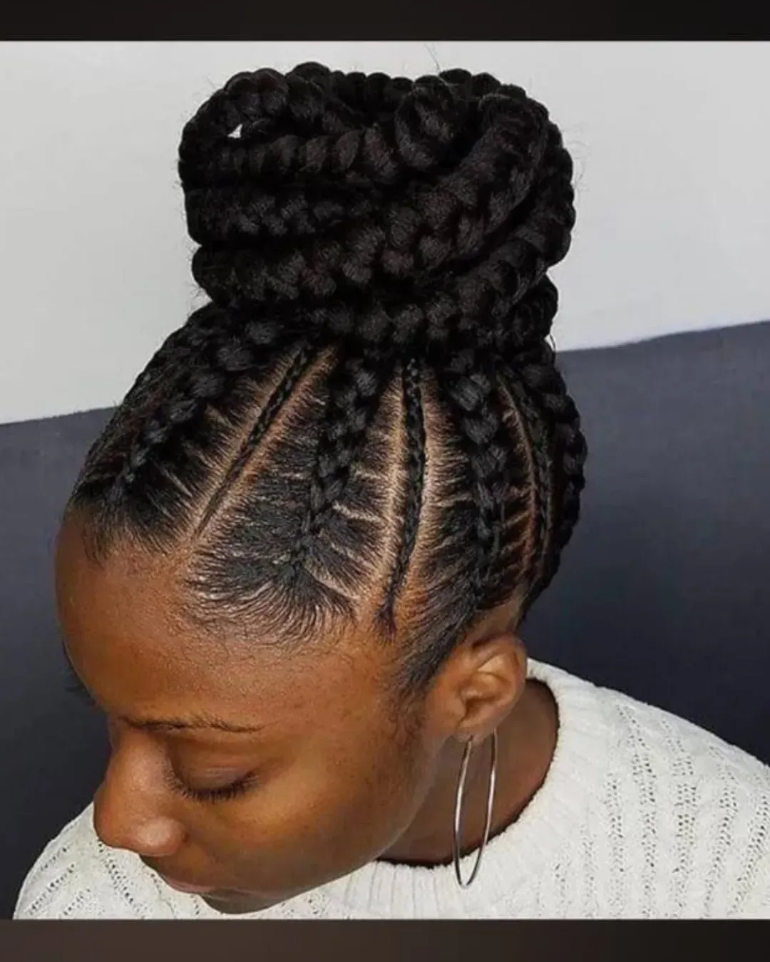 Woman with braided hairstyle, braids framing the face, stacked bun on top.